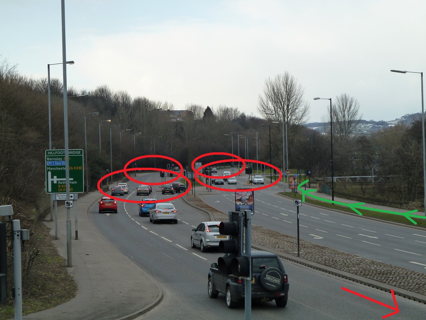  There are (almost) 5 sets of traffic lights controlling the road in this photo. A person using the cycle track checks that it's safe to cross the side road and just goes.   This convenience could be improved by providing cyclists with priority over other traffic when crossing the side road.